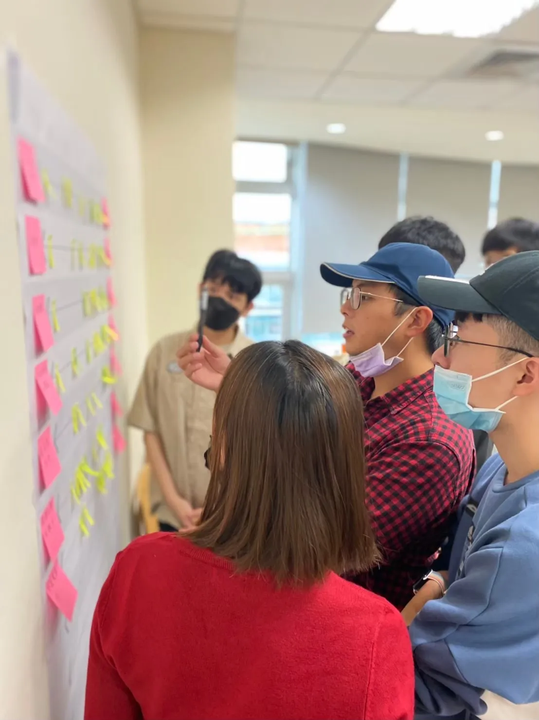 A group of people are sticking post-it notes on the wall.