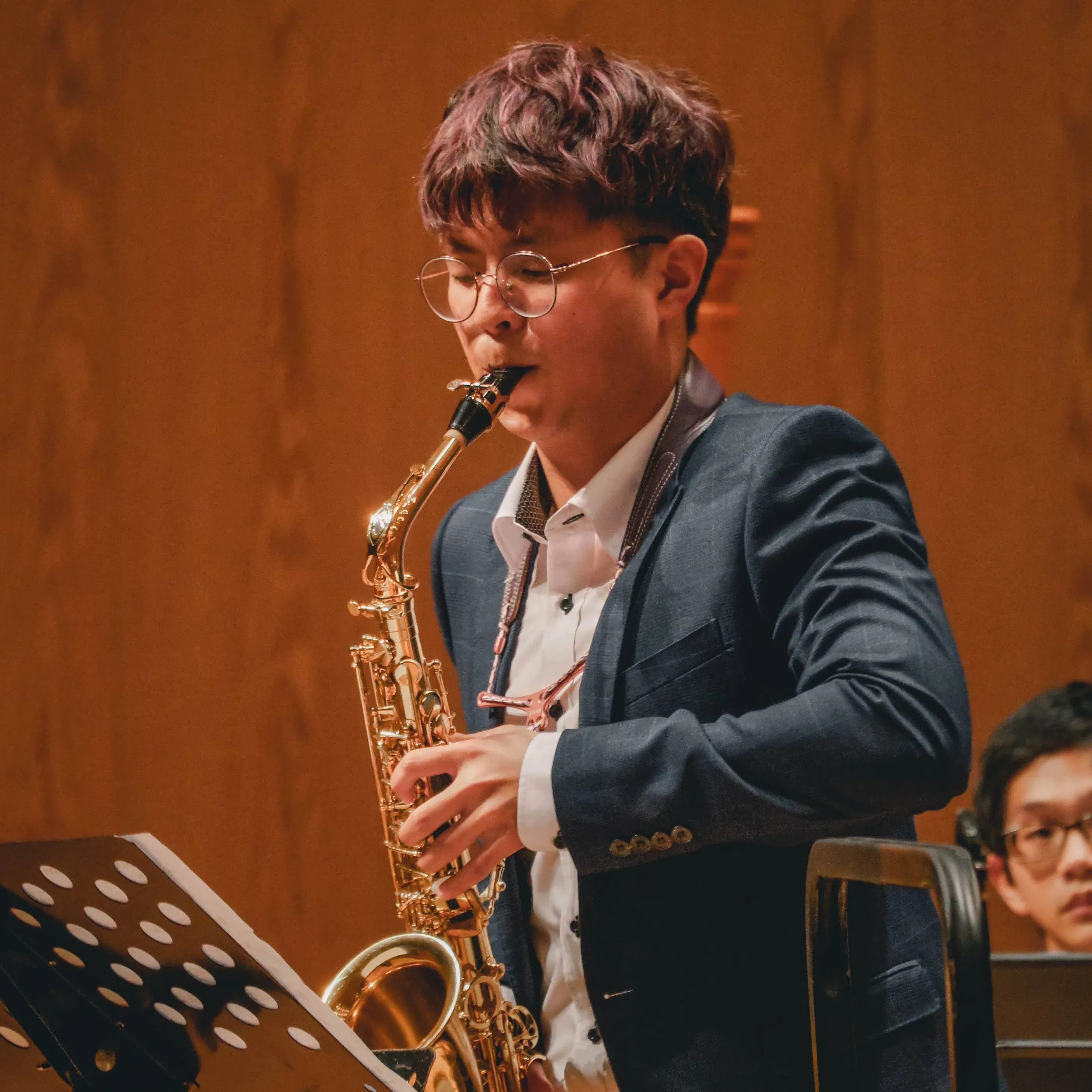 Daniel playing the saxophone in a concert hall.