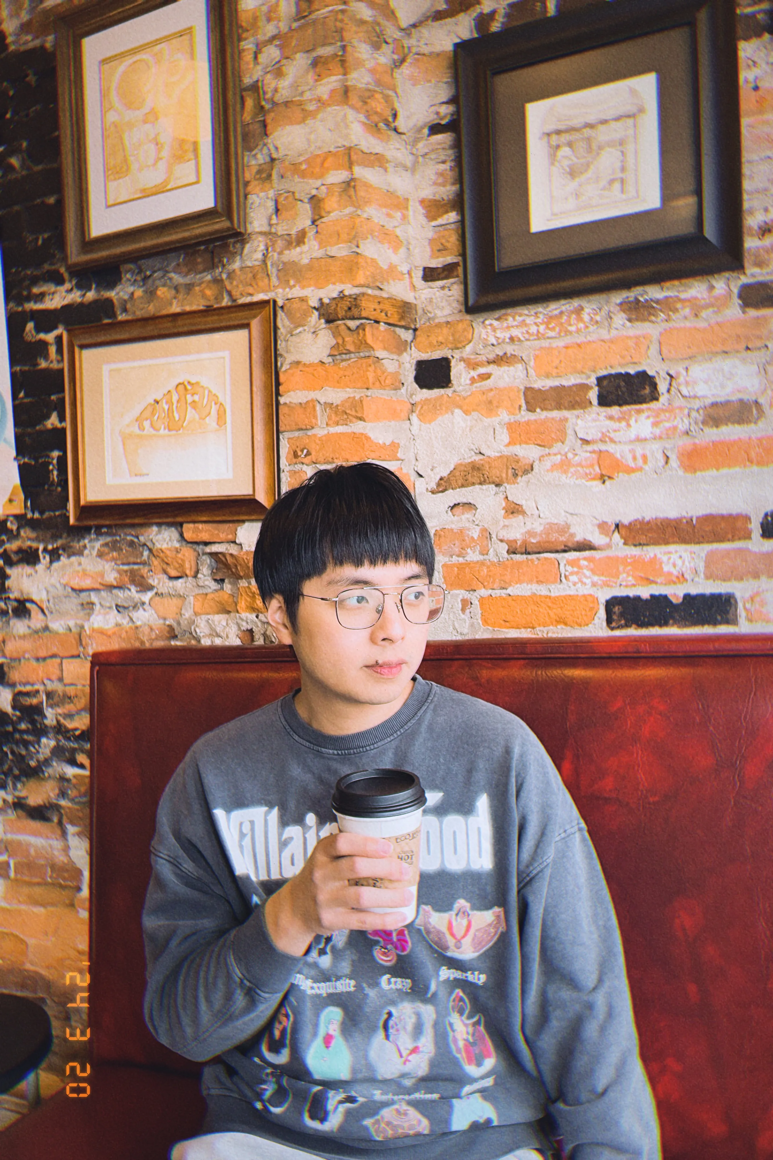 Daniel holding a cup of coffee and looking at outside through a window.